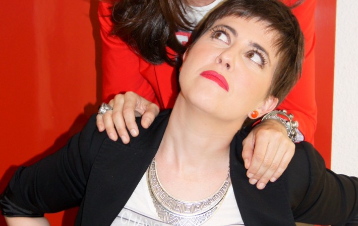 Retrato divertido: una de ellas mira hacia arriba con las manos de la otra sobre los hombros